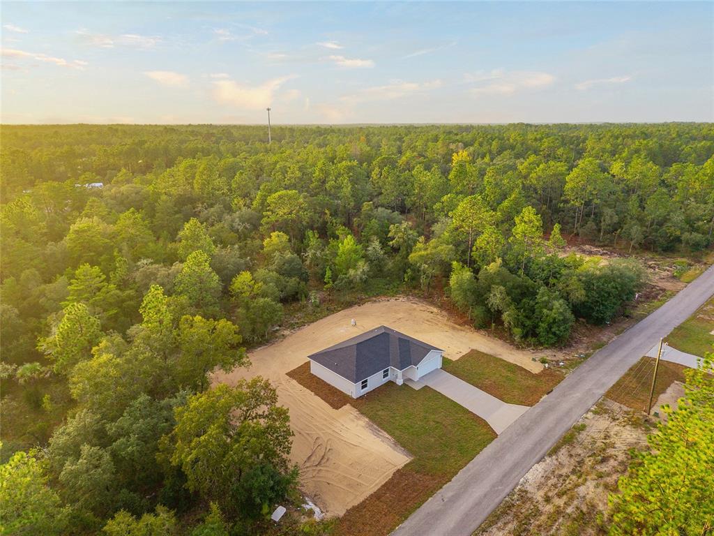 An aerial view shows a newly constructed house surrounded by a dense forest and dirt yard — 2892 SW HARBOR HILLS ROAD, DUNNELLON, FL