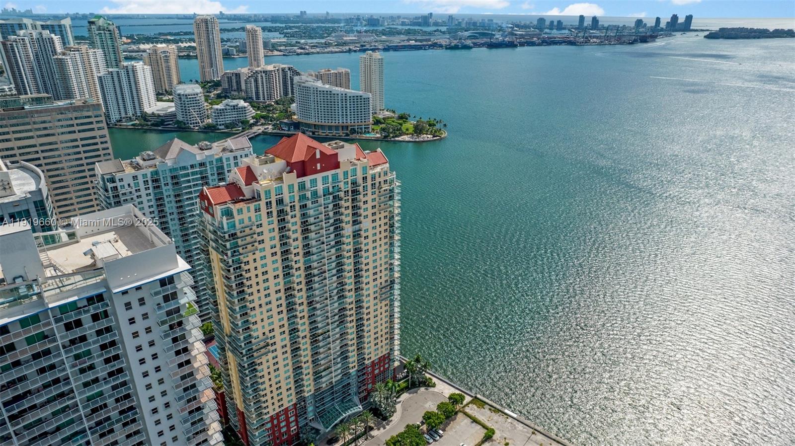An aerial view shows a tall residential building with a red roof near water — 1155 Brickell Bay Dr # 2203, Miami FL 33131, MIAMI, FL