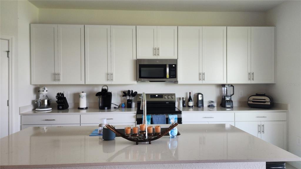 A kitchen features white cabinets, stainless steel appliances, and a large quartz-topped island — 8146 SAINT KITTS CIRCLE, ENGLEWOOD, FL