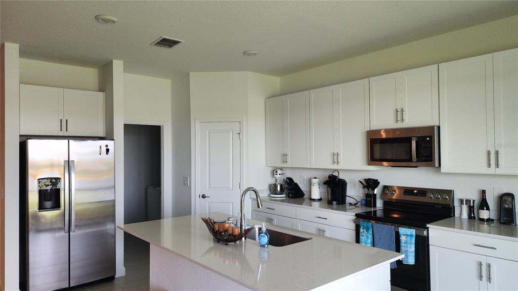 A kitchen features white cabinets, stainless steel appliances, and a central island with a sink — 8146 SAINT KITTS CIRCLE, ENGLEWOOD, FL