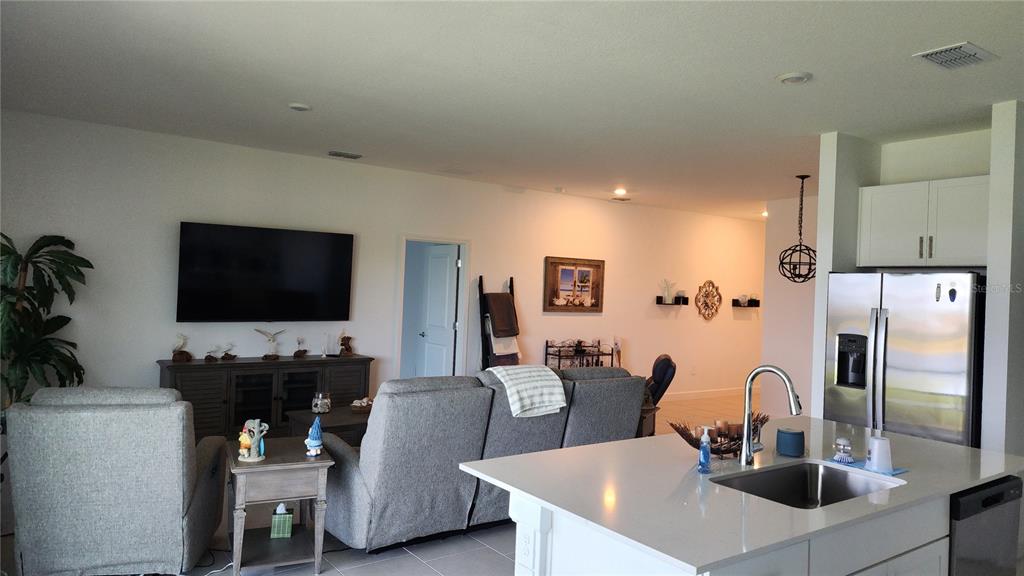 A view of an open-concept living room and kitchen with a large island and television — 8146 SAINT KITTS CIRCLE, ENGLEWOOD, FL