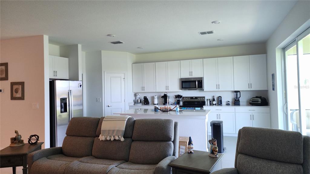 A kitchen with white cabinets and a central island overlooks a living area with sofas — 8146 SAINT KITTS CIRCLE, ENGLEWOOD, FL