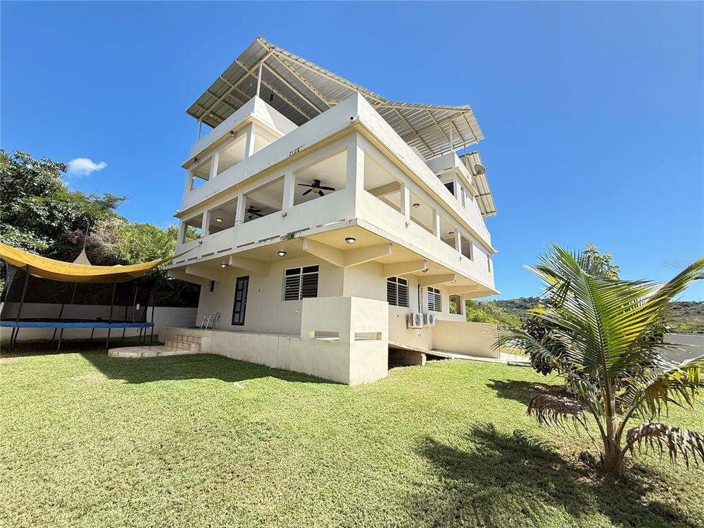 A three-story, light-colored concrete house with a metal roof stands on a grassy lawn — Villa Borinquen BARRIO SANTA MARIA UNIT 376 & 377, VIEQUES, PR