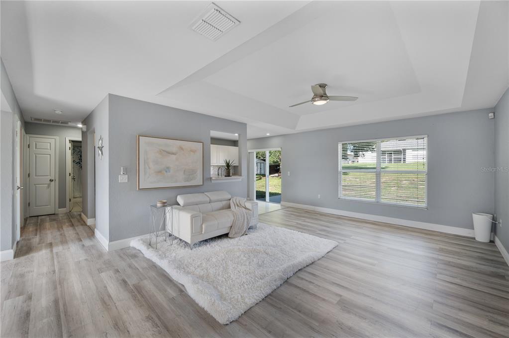 A living room features light gray walls, wood-look flooring, a white sofa, and a tray ceiling — 6059 HILLSIDE HEIGHTS DRIVE, LAKELAND, FL