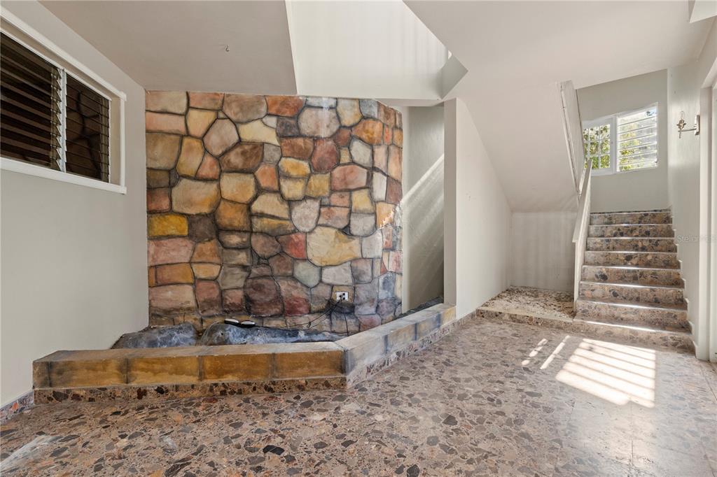 An indoor entryway features a stone accent wall, a small fountain basin, and a staircase — 1 EL MIRADOR DE SAN JUAN, SAN JUAN, PR