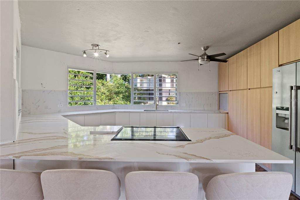 A modern kitchen features white marble countertops, light wood cabinetry, and a large window — 1 EL MIRADOR DE SAN JUAN, SAN JUAN, PR