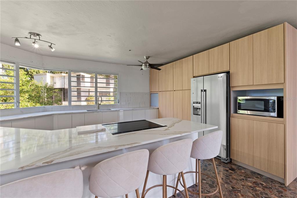 A modern kitchen features light wood cabinetry, a white marble island, and stainless steel appliances — 1 EL MIRADOR DE SAN JUAN, SAN JUAN, PR