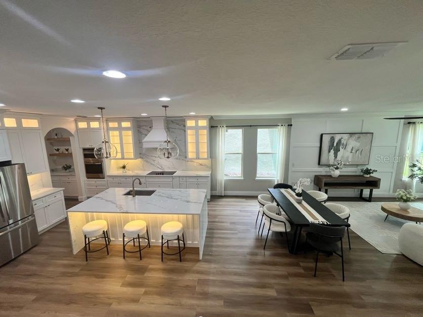 A modern kitchen features a marble-topped island, white cabinetry, and an adjacent dining area — 10169 SHALLOW WATER DRIVE, WINTER GARDEN, FL