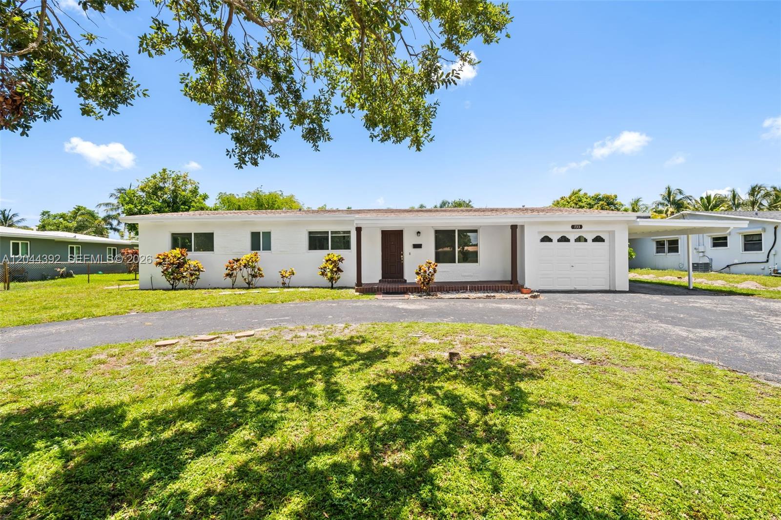 A single-story white house with a front porch, garage, and a large grassy yard — 733 N Rainbow Dr, Hollywood FL 33021, HOLLYWOOD, FL