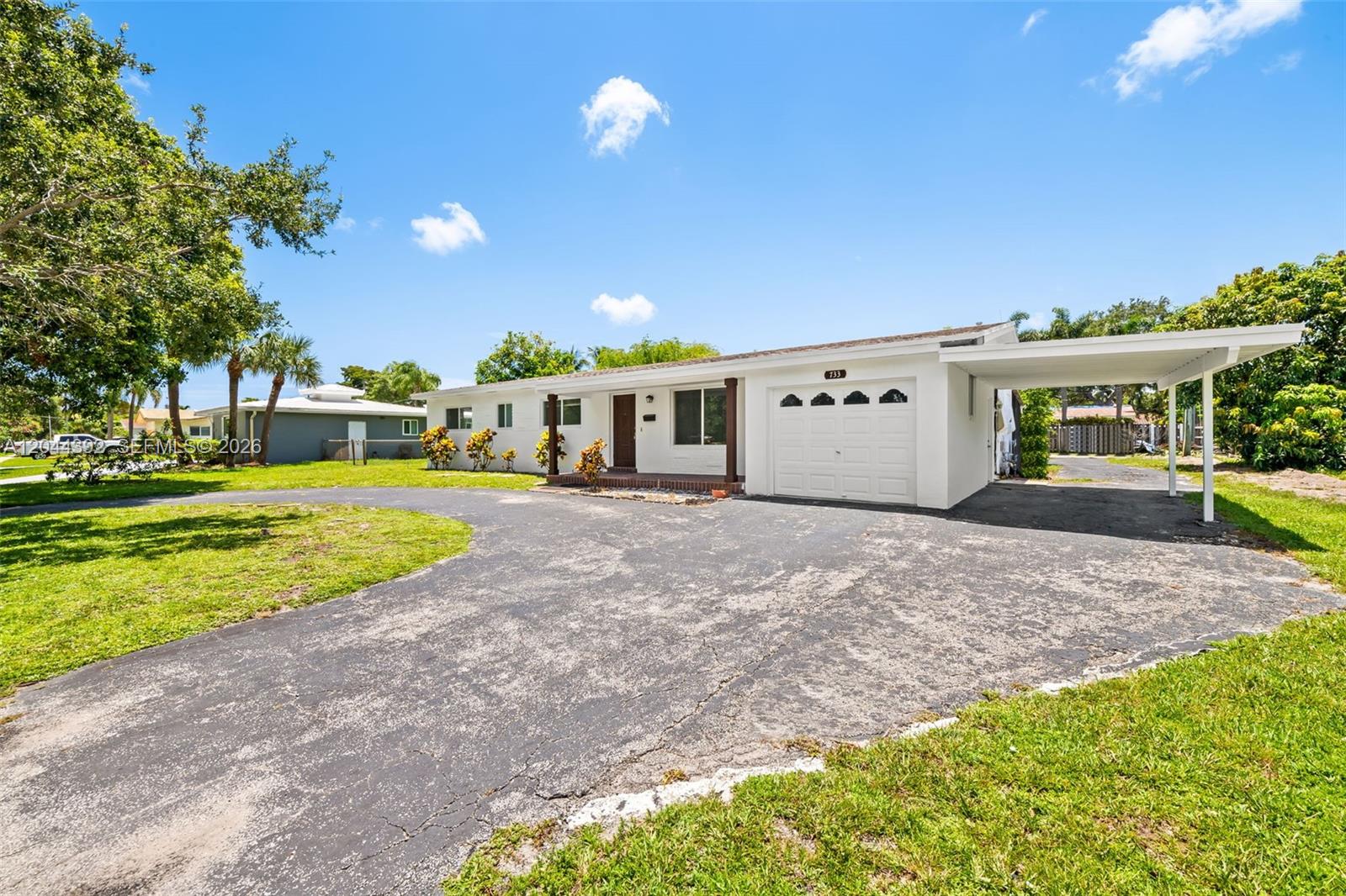 A white single-story house features a large asphalt driveway, a garage, and a carport — 733 N Rainbow Dr, Hollywood FL 33021, HOLLYWOOD, FL