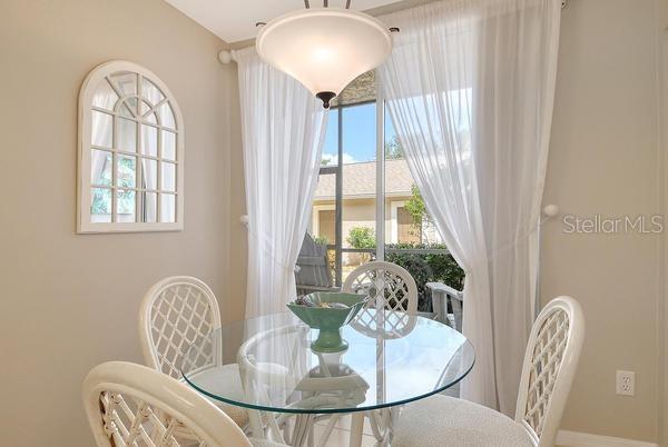 A dining area features a glass-topped table, four white chairs, and a window with curtains — 9641 CASTLE POINT DRIVE UNIT 1215, SARASOTA, FL