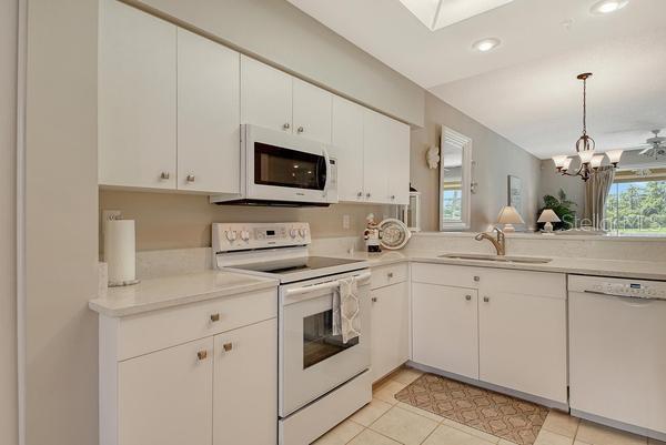 A kitchen with white cabinets, white appliances, and light-colored countertops — 9641 CASTLE POINT DRIVE UNIT 1215, SARASOTA, FL