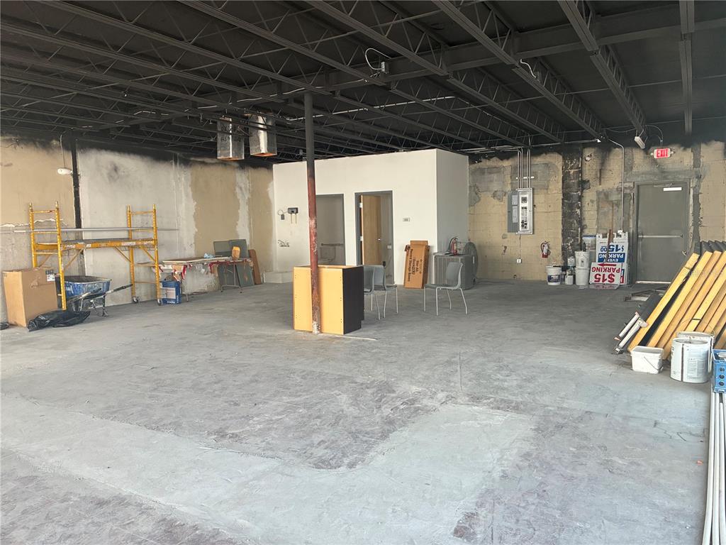 An unfinished commercial space features exposed ceiling joists, concrete floors, and a central restroom enclosure — 646 W CHURCH STREET, ORLANDO, FL