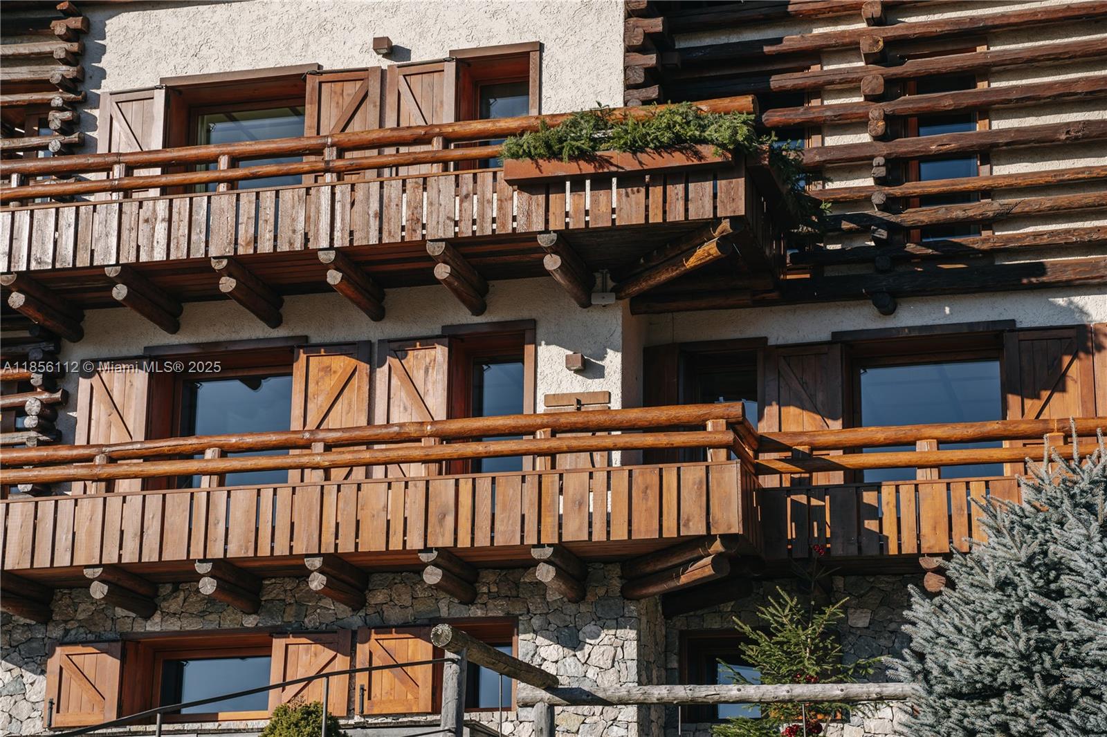 The exterior of a multi-story building features wooden balconies, log accents, and stone wall cladding — Loc. Gilardon 57, Cortina Località Gilardon, FL, FL