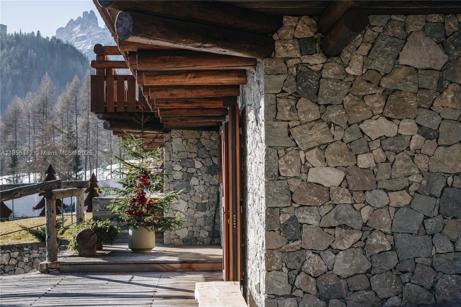 A stone-walled cabin exterior features a wooden deck, exposed log beams, and a decorated tree — Loc. Gilardon 57, Cortina Località Gilardon, FL, FL