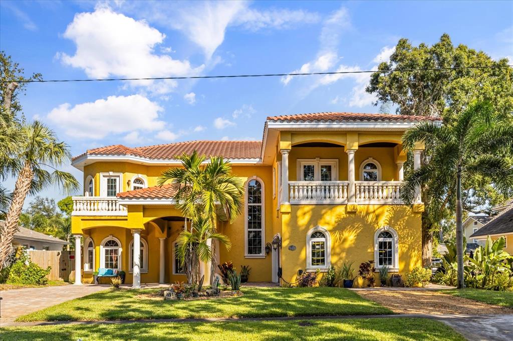 A two-story yellow stucco house with a tile roof, balconies, and a palm tree — 911 JUNGLE AVENUE N, ST PETERSBURG, FL