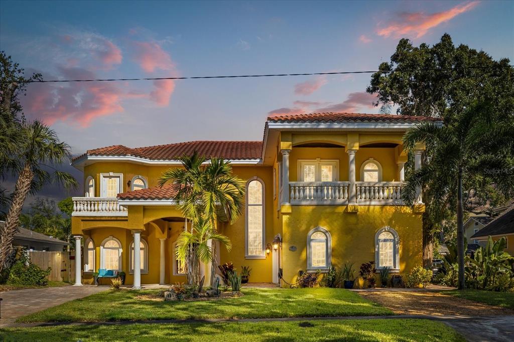 A two-story yellow stucco house with a red tile roof and a second-floor balcony — 911 JUNGLE AVENUE N, ST PETERSBURG, FL