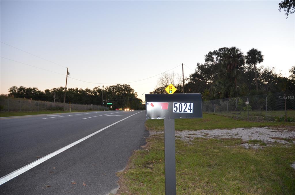 A mailbox with the number 5024 stands beside a paved road at dusk — 5024 PLYMOUTH SORRENTO ROAD, APOPKA, FL