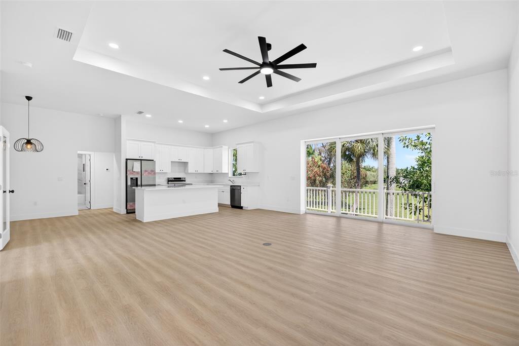 A bright, open-concept living area with white cabinets, a kitchen island, and sliding glass doors — 200 LEACH DRIVE, PUNTA GORDA, FL