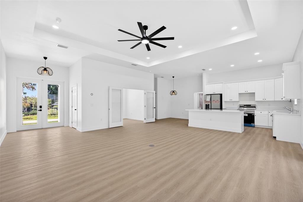 An open-concept living area features a kitchen with white cabinetry, light wood flooring, and a tray ceiling — 200 LEACH DRIVE, PUNTA GORDA, FL