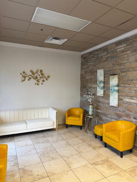 A waiting room features a white sofa, two yellow chairs, and a stone accent wall — 8010 SUNPORT DRIVE UNIT #116, ORLANDO, FL