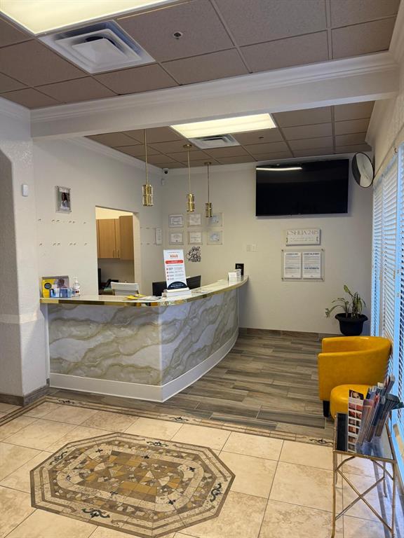 A reception area features a curved marble-patterned desk, yellow chairs, and a tiled floor — 8010 SUNPORT DRIVE UNIT #116, ORLANDO, FL