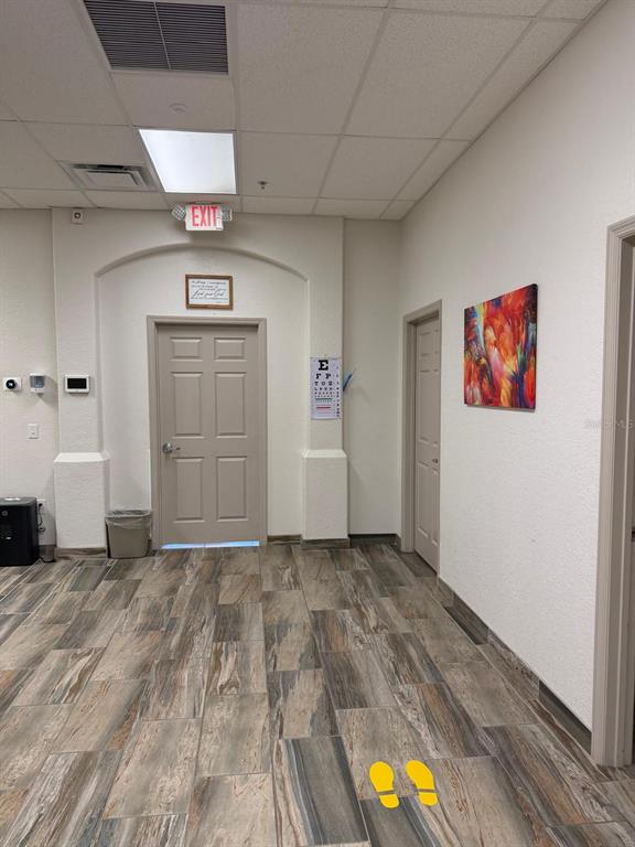 A room with wood-look tile flooring, two doors, an eye chart, and an exit sign — 8010 SUNPORT DRIVE UNIT #116, ORLANDO, FL