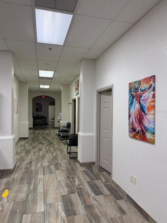 A hallway with wood-look tile flooring, white walls, recessed lighting, and framed artwork — 8010 SUNPORT DRIVE UNIT #116, ORLANDO, FL