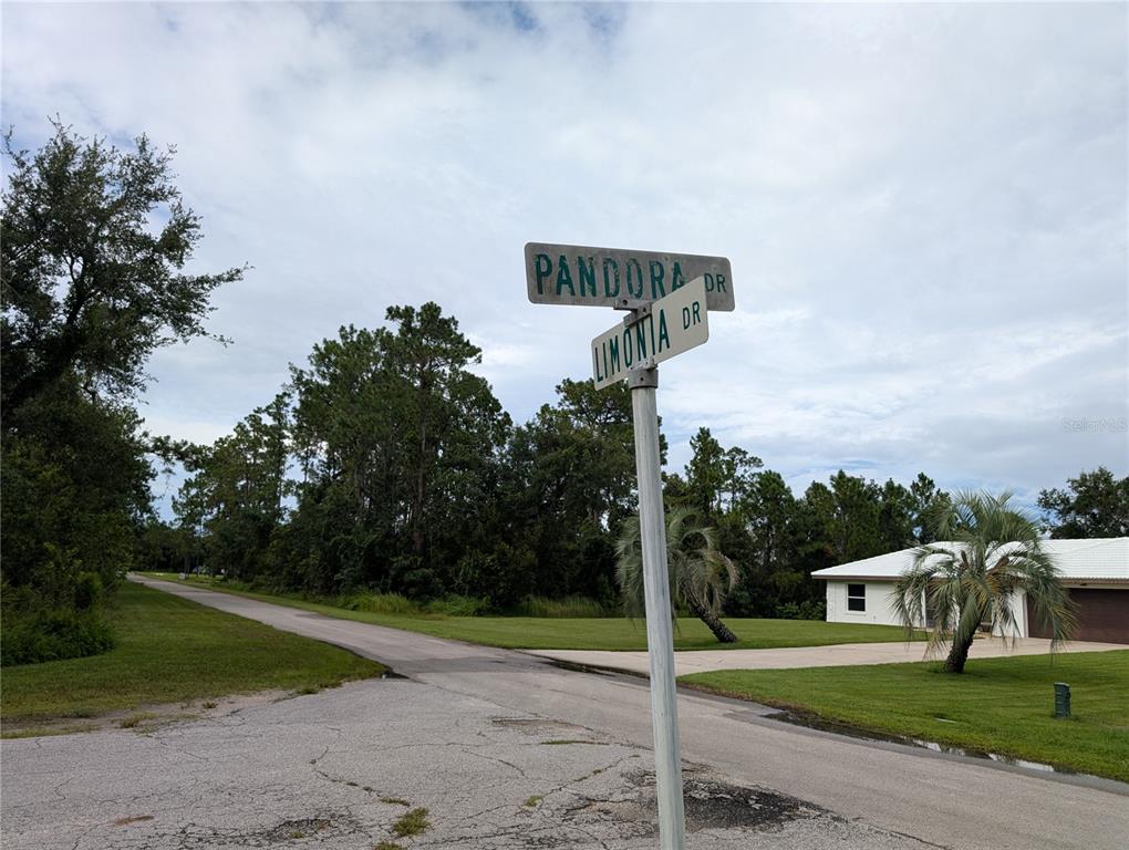 A street sign for Pandora Drive and Limonia Drive stands at a paved intersection — 302 PANDORA DRIVE, INDIAN LAKE ESTATES, FL
