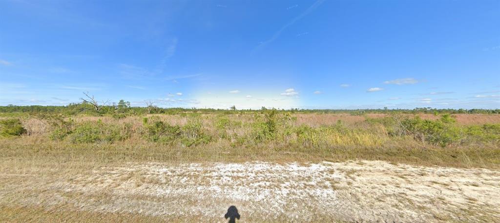 A wide, flat, undeveloped grassy lot under a clear blue sky — 514 PORTULACA DRIVE, INDIAN LAKE ESTATES, FL