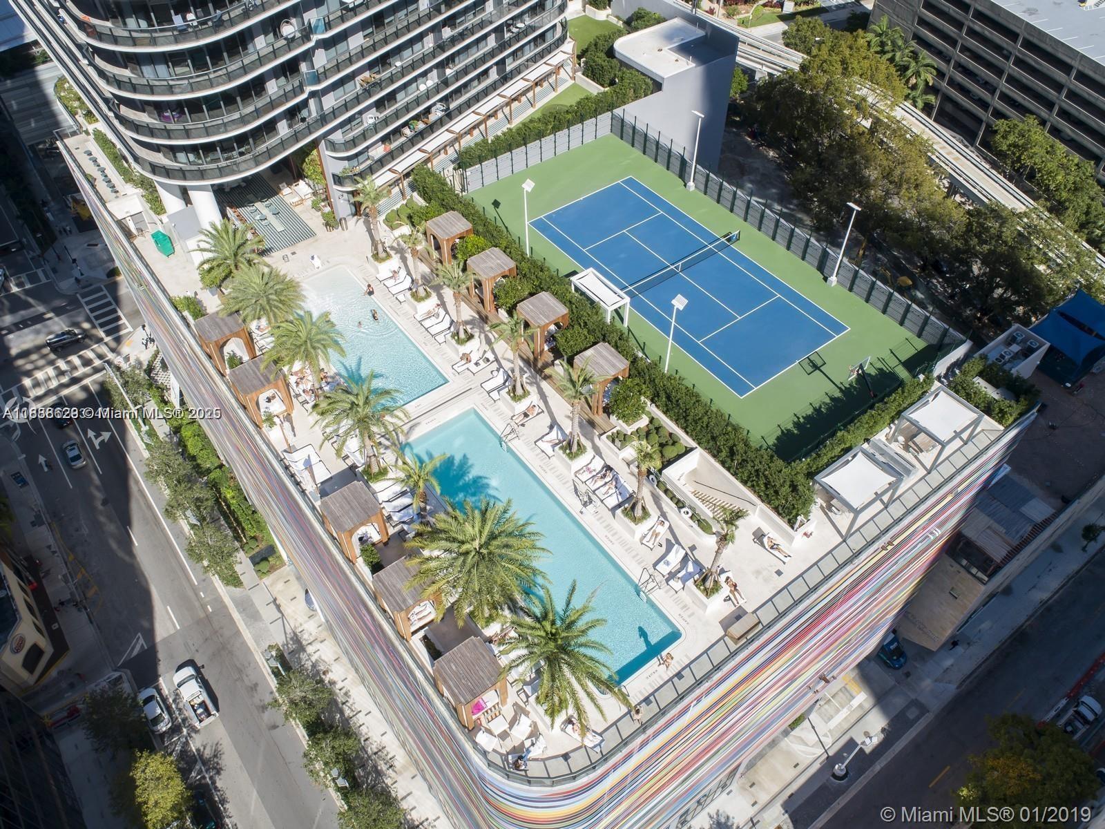 An aerial view shows a rooftop terrace with two swimming pools and a tennis court — 801 S Miami Ave # 3304, Miami FL 33130, MIAMI, FL