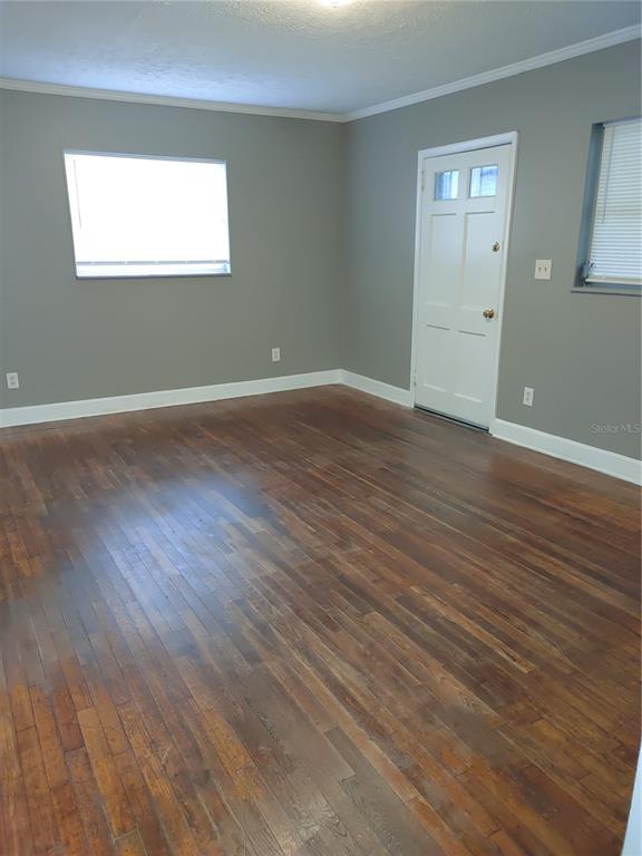 An empty room features gray walls, hardwood floors, a white door, and two windows — 1090 SAINT CLAIR STREET, JACKSONVILLE, FL