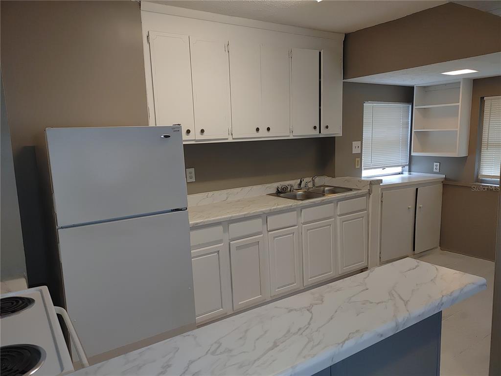 A kitchen features white cabinets, a marble-patterned countertop, and a white refrigerator — 1090 SAINT CLAIR STREET, JACKSONVILLE, FL