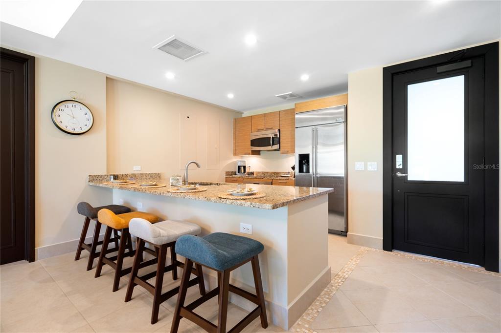 A kitchen features a granite-topped island with four bar stools and stainless steel appliances — 7000 BAHIA BEACH BLV LAS VERANDAS UNIT 3118, RIO GRANDE, PR