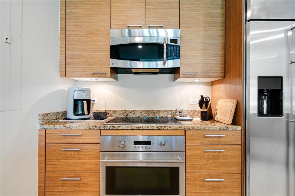A kitchen features wood-grain cabinets, stainless steel appliances, and granite countertops — 7000 BAHIA BEACH BLV LAS VERANDAS UNIT 3118, RIO GRANDE, PR