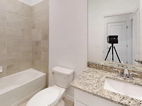 A bathroom features a tiled shower-tub combo, a white toilet, and a granite-topped vanity — 2017 GARDENIA AVENUE, PORT CHARLOTTE, FL