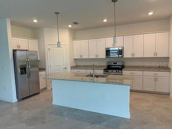 A kitchen features white cabinets, granite countertops, a stainless steel refrigerator, and a central island — 2017 GARDENIA AVENUE, PORT CHARLOTTE, FL