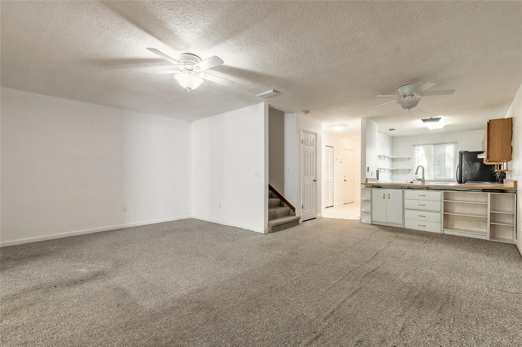 A living room with gray carpet, a ceiling fan, and an open kitchen area — 3548 FOREST BRANCH DRIVE UNIT C, PORT ORANGE, FL