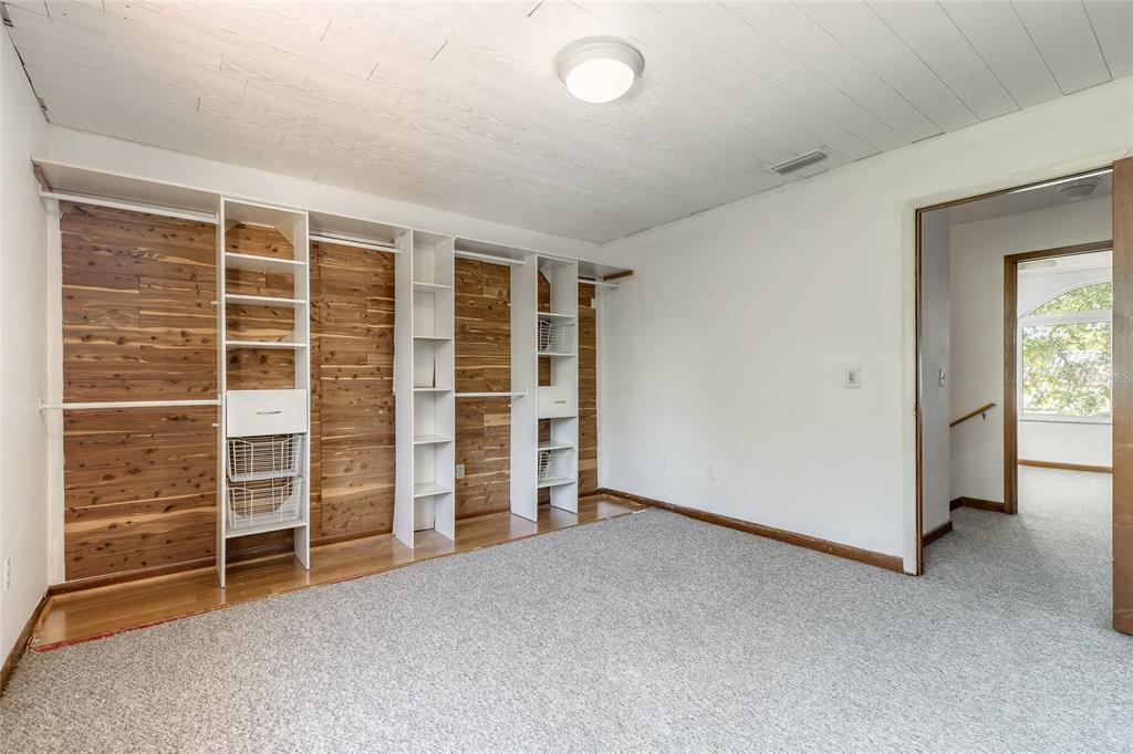 A bedroom features a cedar-paneled closet wall with white shelving and gray carpeted flooring — 3548 FOREST BRANCH DRIVE UNIT C, PORT ORANGE, FL
