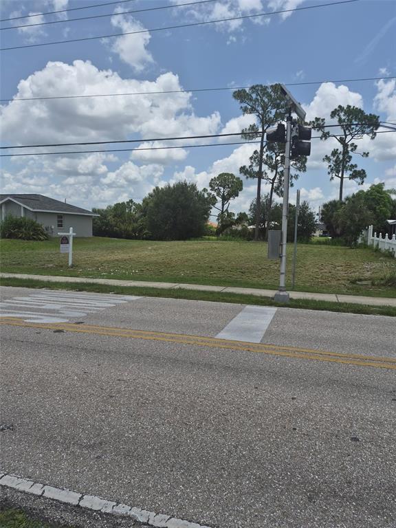 A vacant, grassy residential lot sits next to a house with a real estate sign — 23326 PEACHLAND BOULEVARD, PORT CHARLOTTE, FL