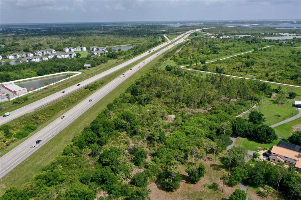 An aerial view shows a highway running alongside a large, undeveloped wooded lot — 24869 NOVA LANE, PORT CHARLOTTE, FL