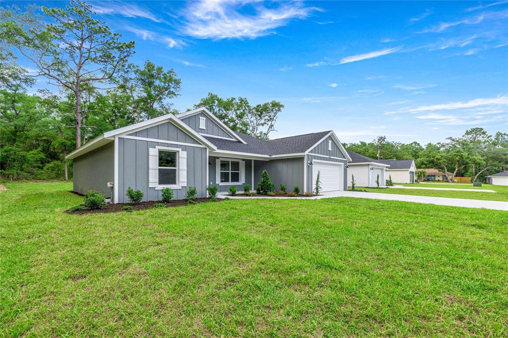 A gray, single-story house with white trim and a two-car garage sits on a lawn — 4056 SW 156TH COURT, OCALA, FL