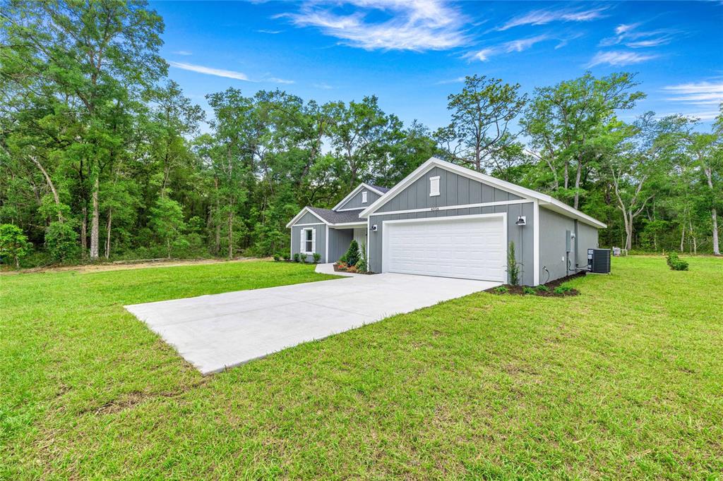 A gray single-story house with a white garage door sits on a grassy lot — 4056 SW 156TH COURT, OCALA, FL