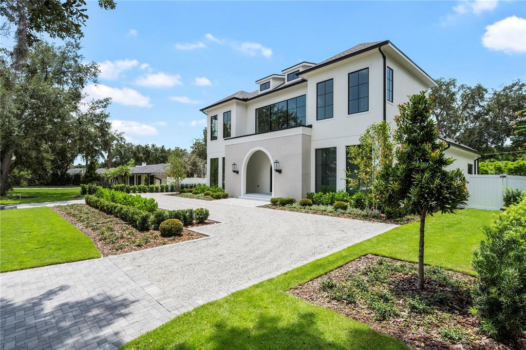 A modern two-story house with a gravel driveway, arched entryway, and manicured landscaping — 1525 GRANVILLE DRIVE, WINTER PARK, FL
