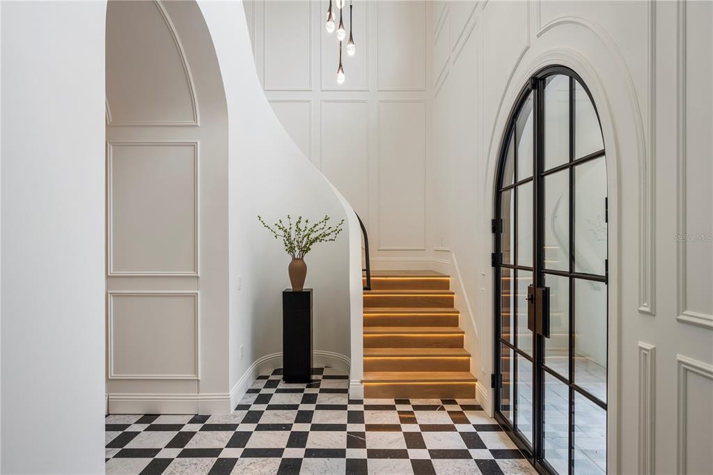 A foyer features a black and white checkered floor, arched glass doors, and wooden stairs — 1525 GRANVILLE DRIVE, WINTER PARK, FL