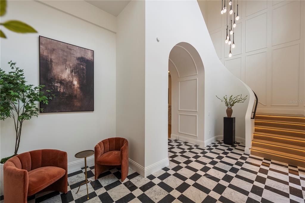 A foyer features a checkered marble floor, an arched doorway, and a curved wooden staircase — 1525 GRANVILLE DRIVE, WINTER PARK, FL