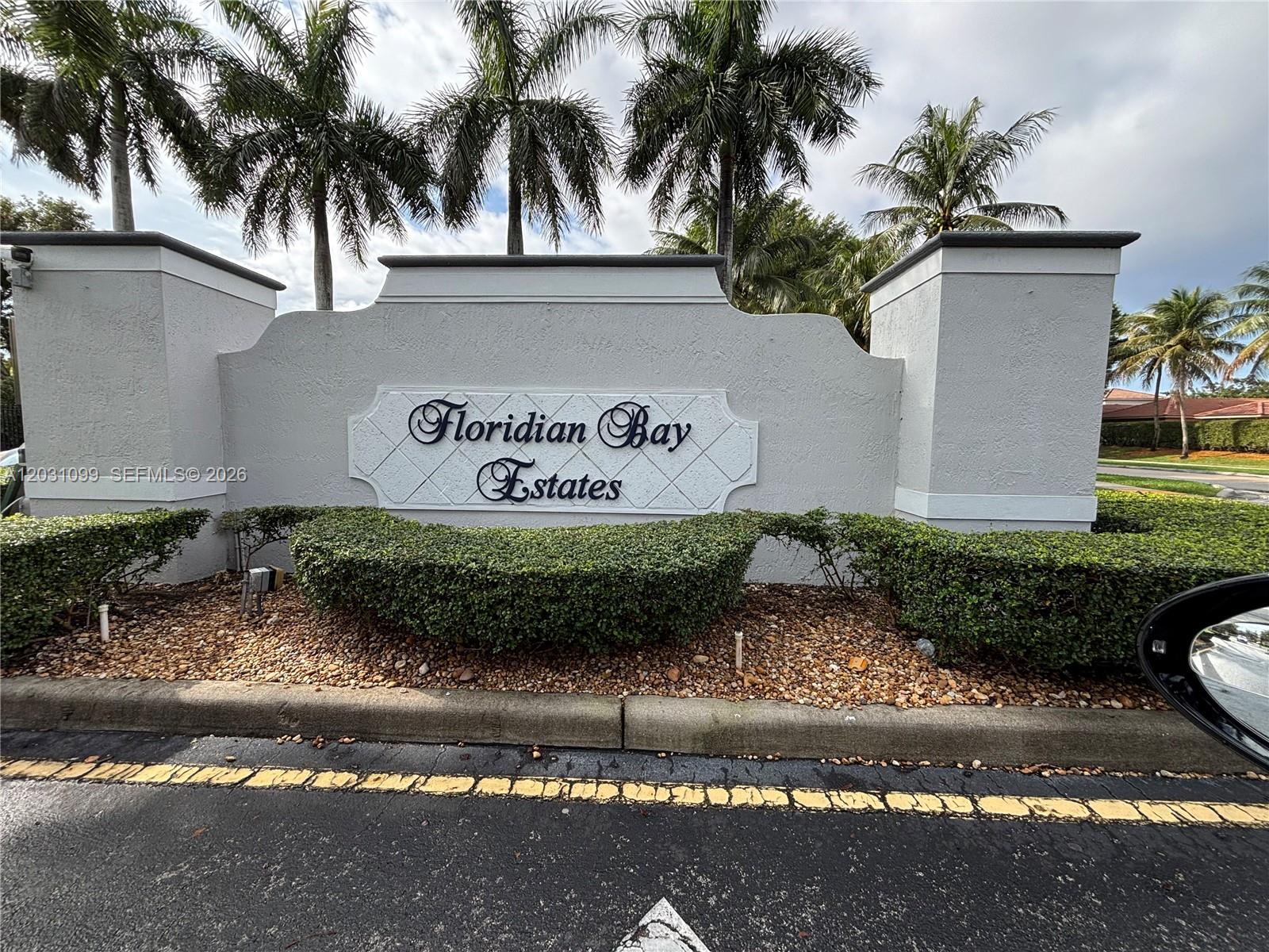 A sign for Floridian Bay Estates stands behind a manicured hedge and palm trees — 2103 NE 38th Rd, Homestead FL 33033, HOMESTEAD, FL