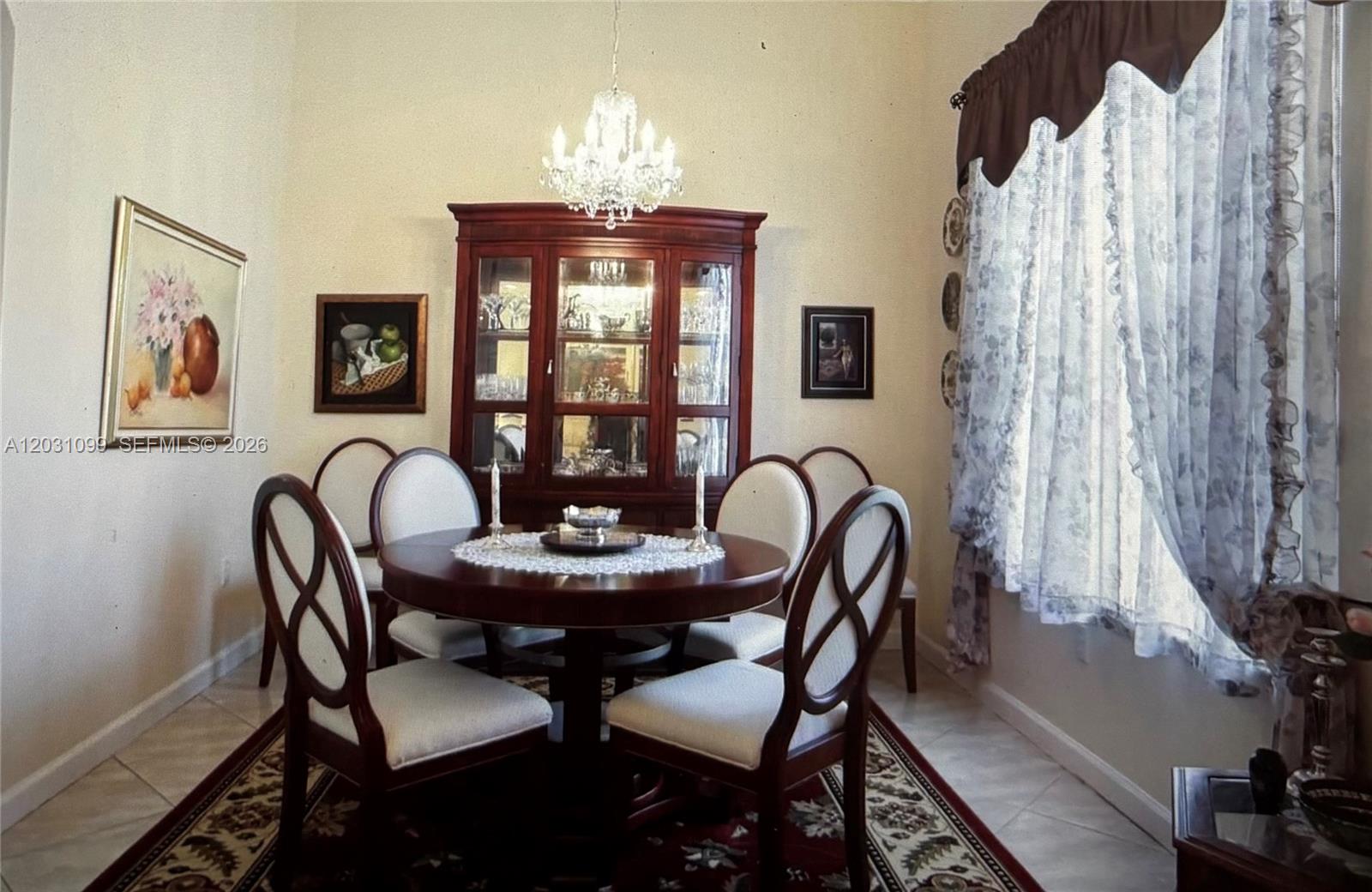 A dining room features a round wooden table, six chairs, and a large china cabinet — 2103 NE 38th Rd, Homestead FL 33033, HOMESTEAD, FL
