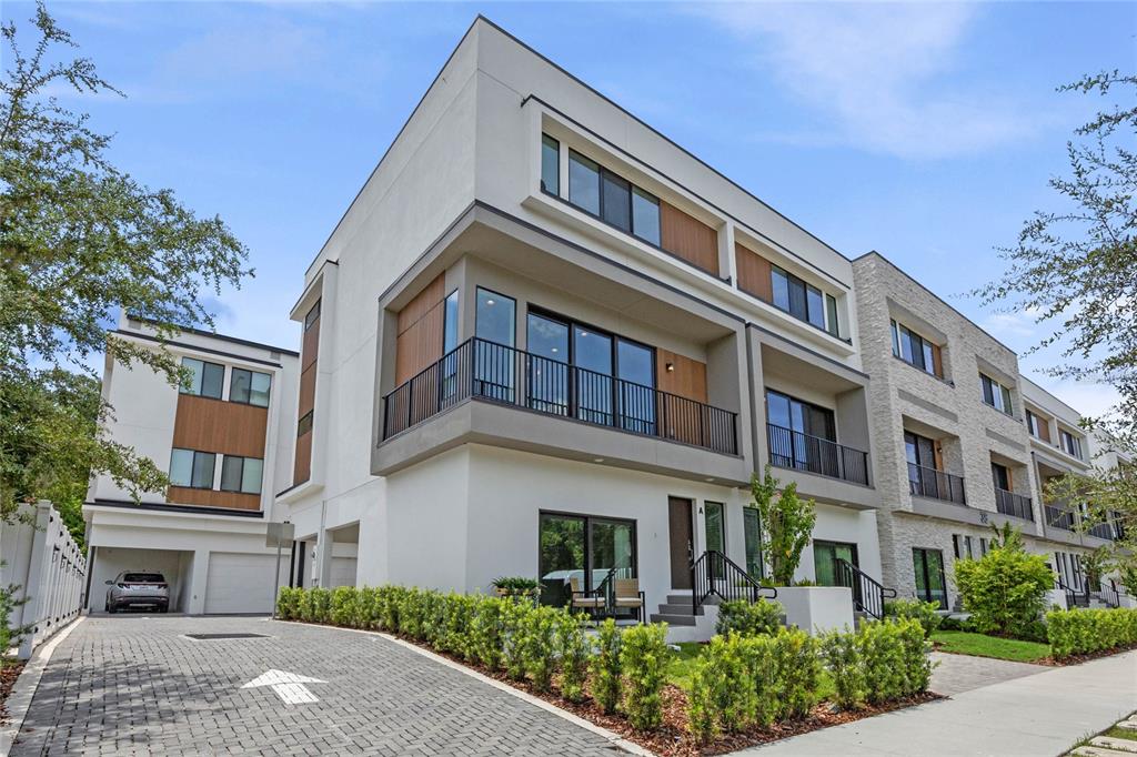 A modern multi-story townhouse with a paved driveway, balconies, and light-colored exterior siding — 52 W HARDING STREET UNIT A, ORLANDO, FL