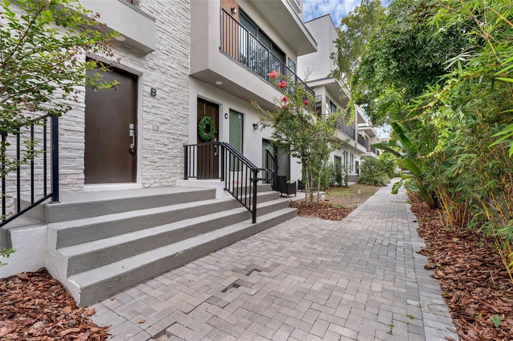 A paved walkway leads to the entrances of two modern townhomes with stone-textured facades — 52 W HARDING STREET UNIT A, ORLANDO, FL